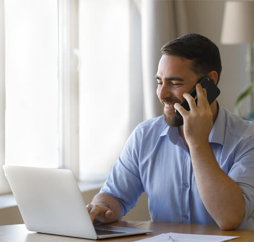 man talking on the phone and looking at laptop